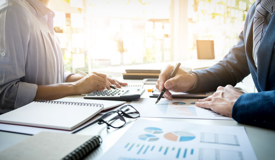 Business professionals working at a table with cards and business tools spread out.