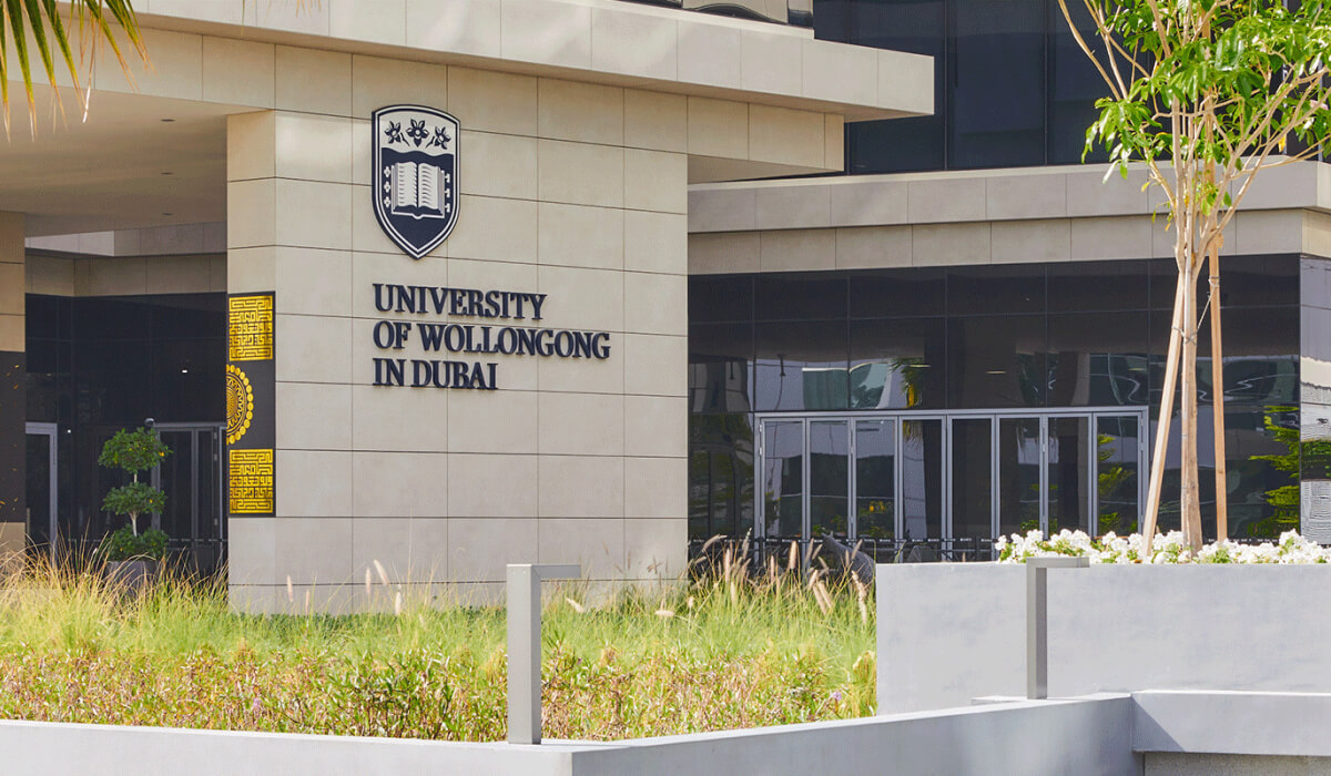 University of Wollongong in Dubai sign on the building, with a partial view of the modern campus architecture.