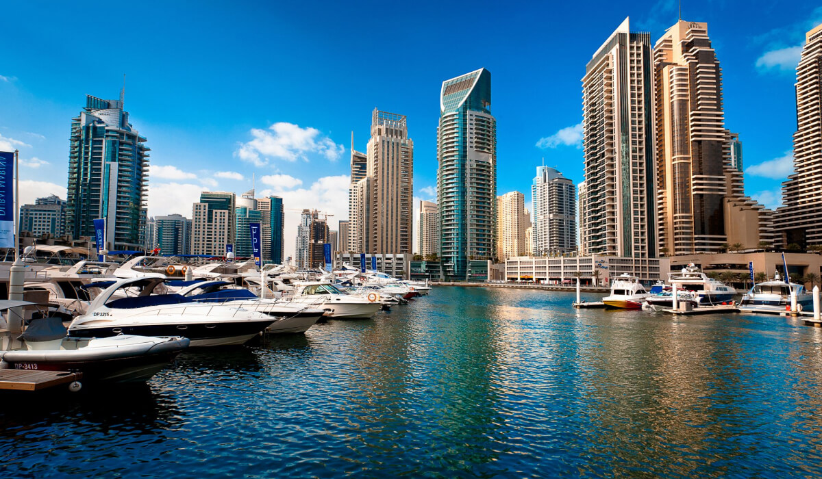 Dubai Marina with calm water in the foreground, filled with yachts, surrounded by modern luxury buildings, showcasing a comfortable and upscale environment.