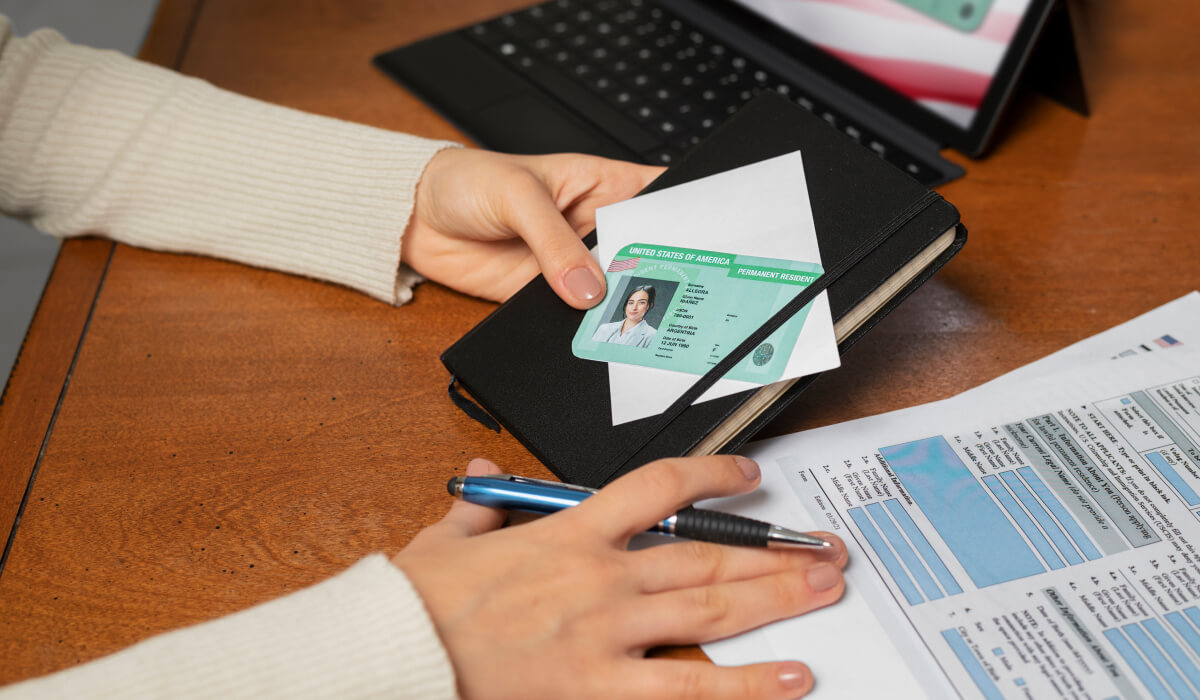 An immigration worker holding an applicant's ID, with supporting documents laid out on the table.