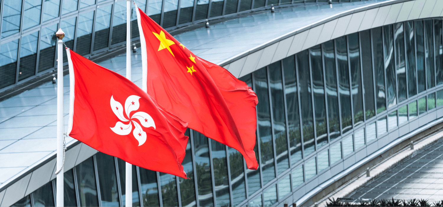 The flags of Hong Kong and China wave in the wind in front of a modern building, symbolizing their presence against a backdrop of sleek, contemporary architecture.