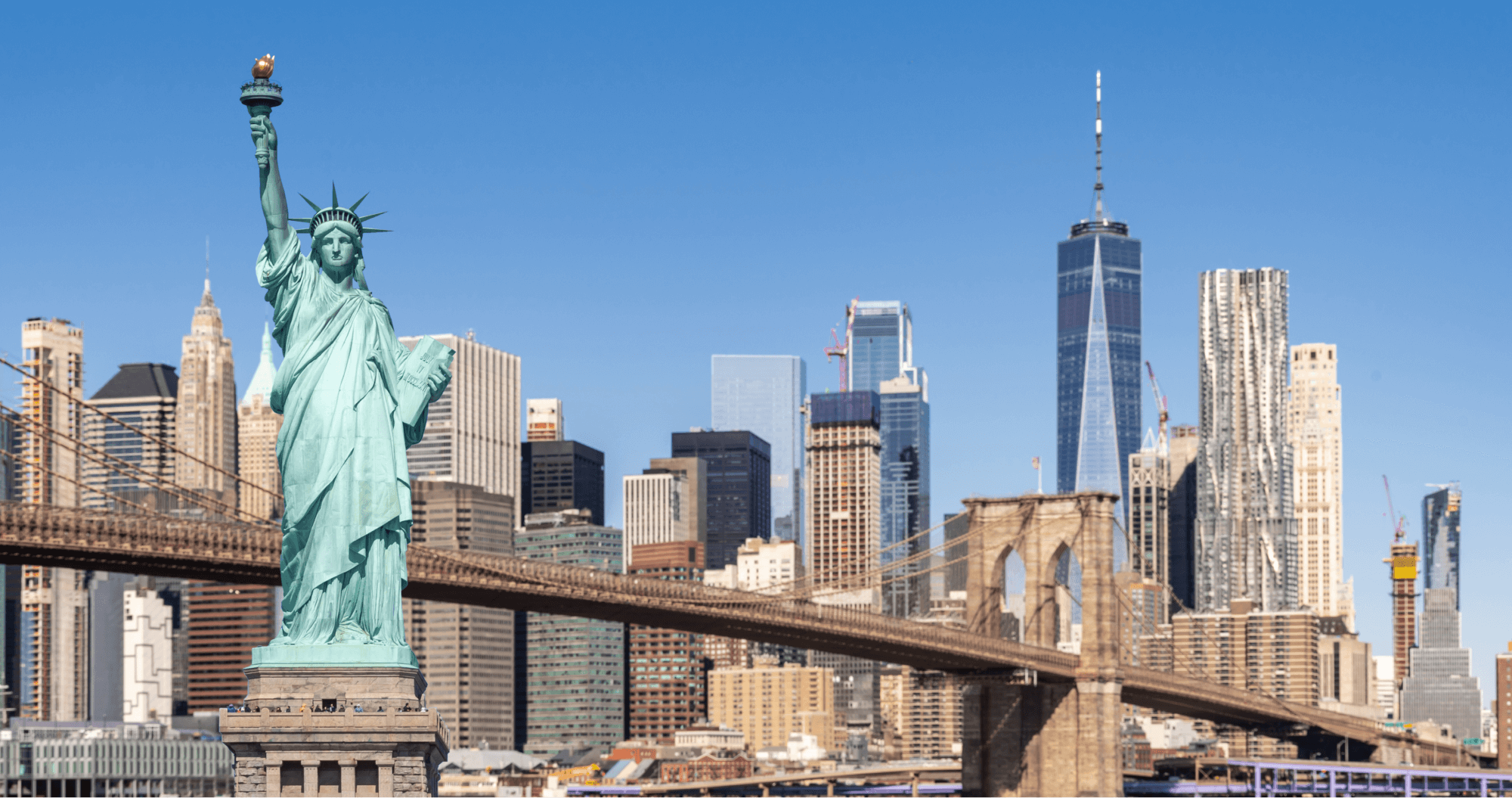 The Statue of Liberty stands tall and bright with the American city skyline in the background, under a clear blue sky, symbolizing freedom and patriotism.