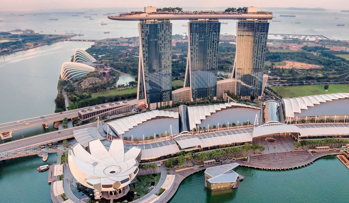 A stunning bridge in Singapore with two modern glass buildings, surrounded by greenery and water, showcasing the perfect blend of nature and futuristic architecture.