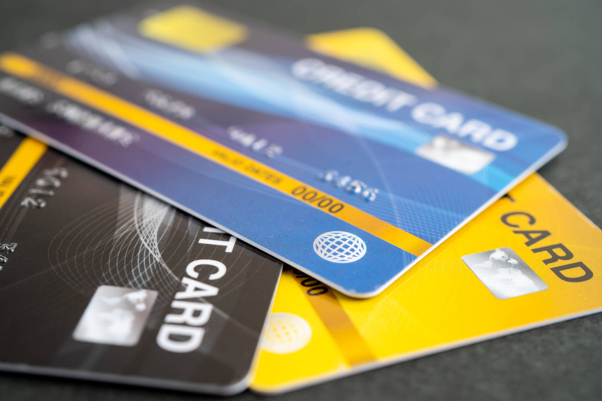 A stack of Georgian bank credit cards in various colors, including yellow, blue, and black, placed on a table.