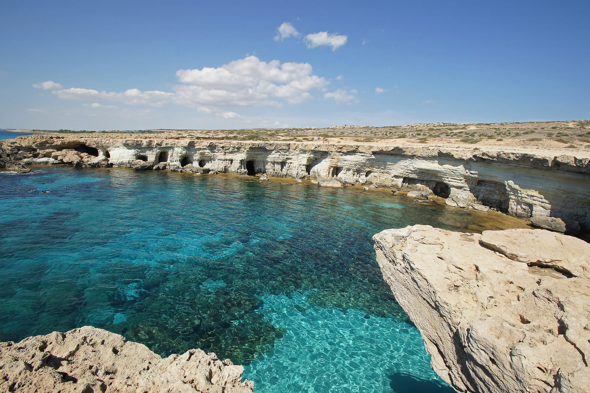 A scenic view of the sea in Cyprus, showcasing beautiful shades of blue with rocky formations surrounding the water.