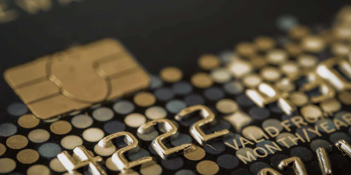 A close-up image of a credit card showcases dark blue and gold colors, with four zoomed-in numbers prominently displayed while the background remains blurred.