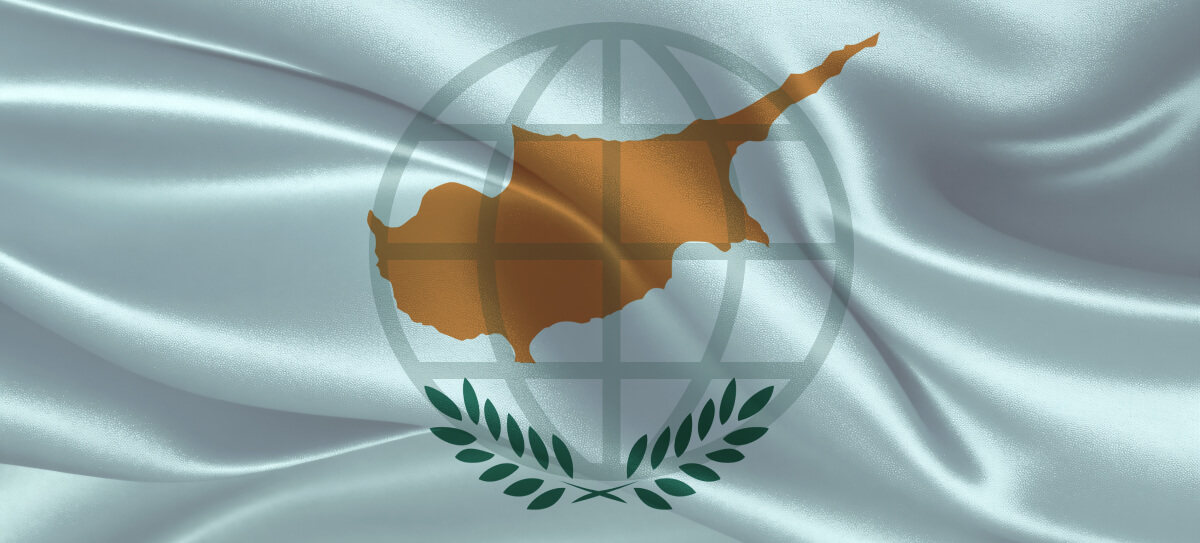 A white textile background featuring the map of Cyprus, overlaid with a transparent world globe image and branches of a tree.