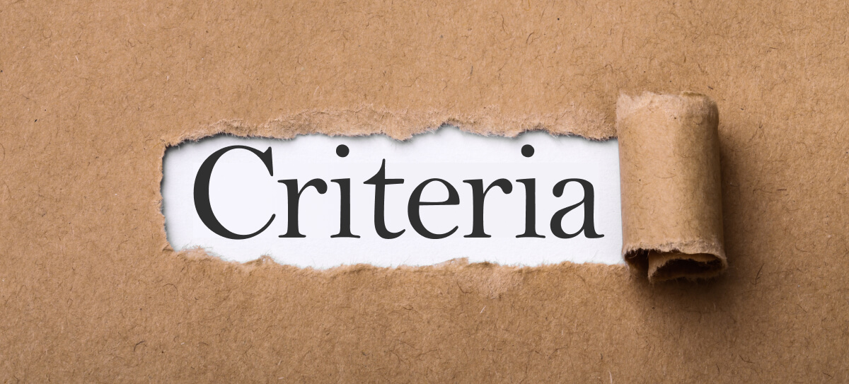 Torn brownish paper revealing the word 'criteria' on a white background underneath.