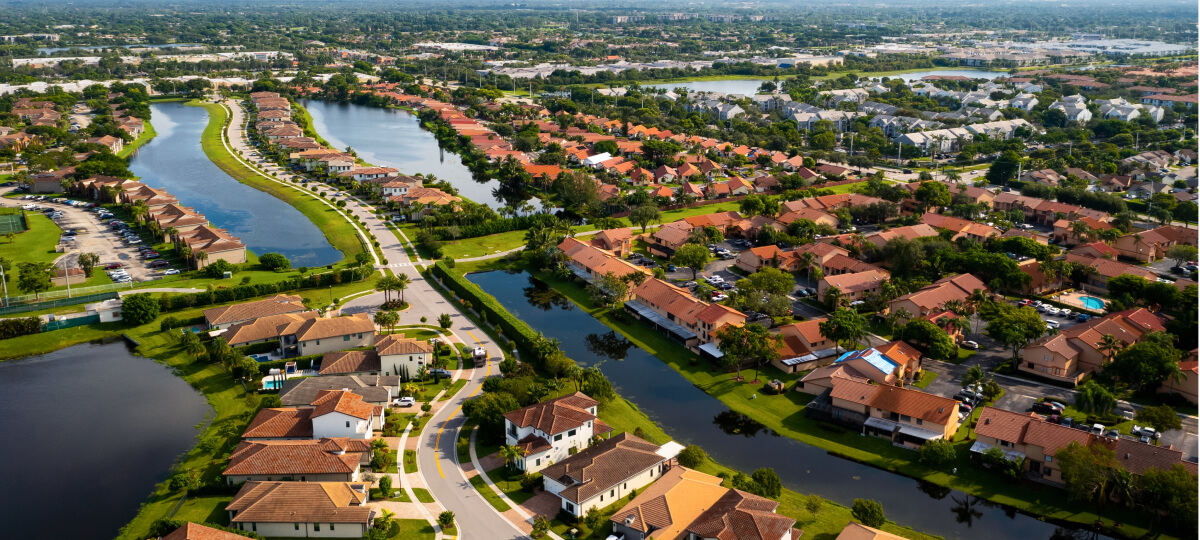 Aerial view of a luxury residential neighborhood in Florida with houses, canals, and green spaces.