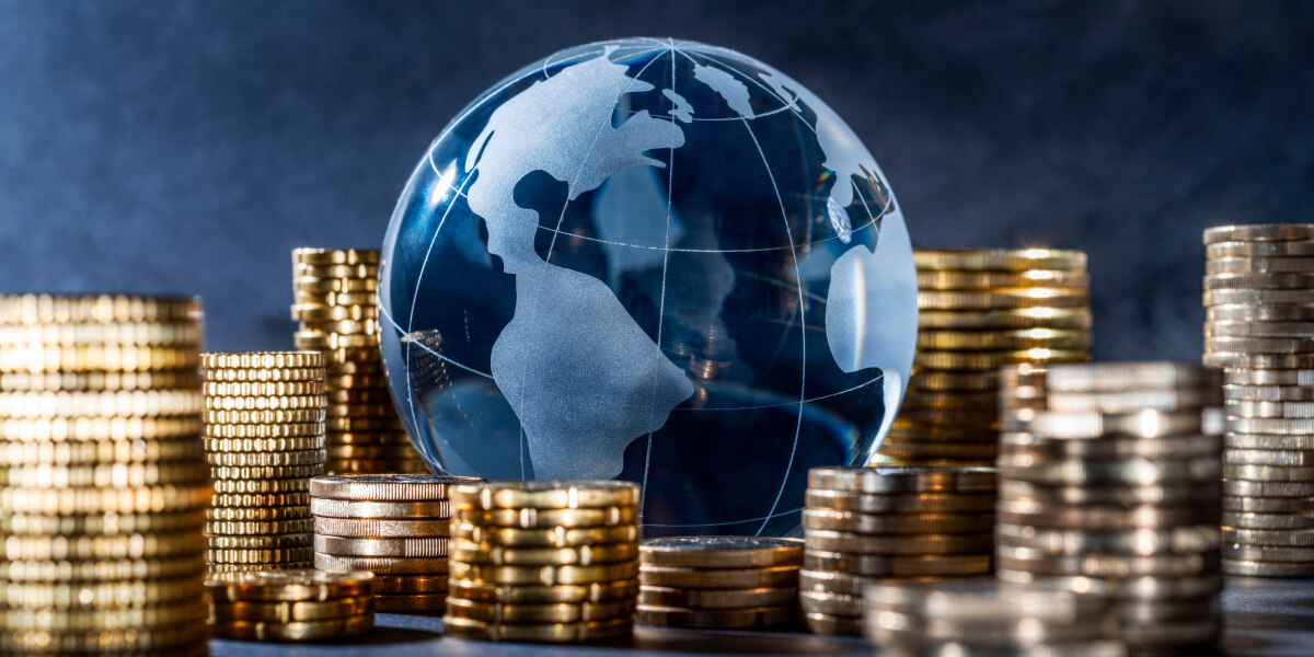 A globe partially surrounded by stacks of coins, symbolizing global finance.