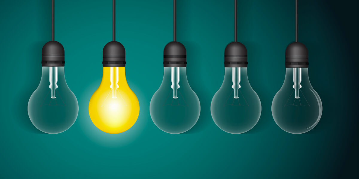 A glowing yellow lightbulb among dimmed bulbs on a teal background.