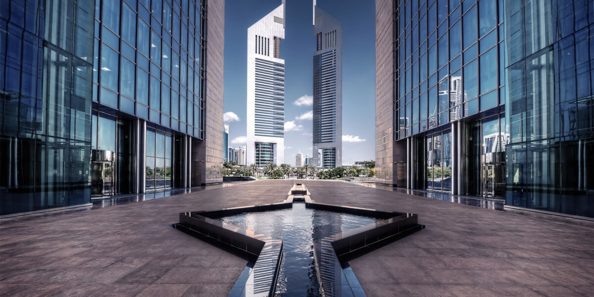 Modern glass skyscrapers with a water feature in an urban setting.