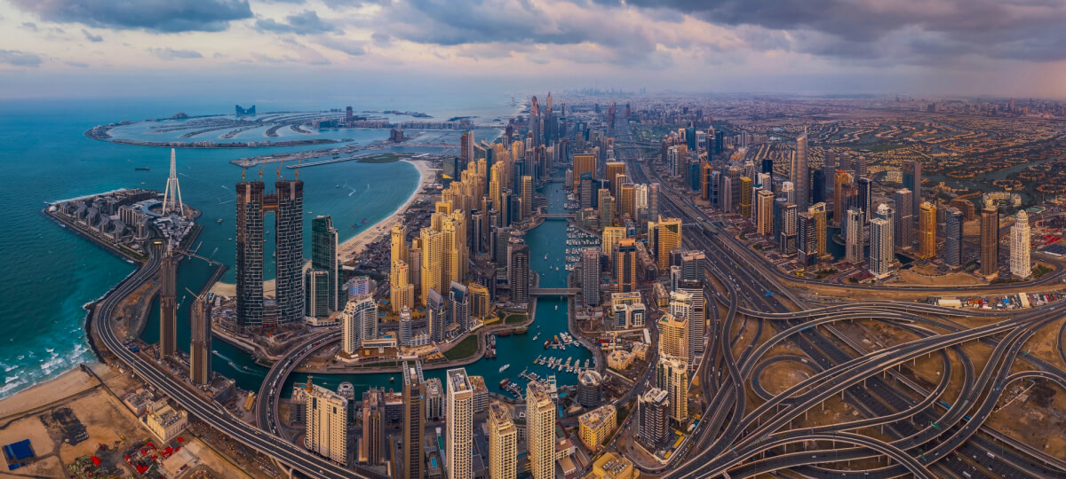 Palm Jumeirah and Dubai Marina skyline at sunset, showcasing iconic waterfront real estate developments.