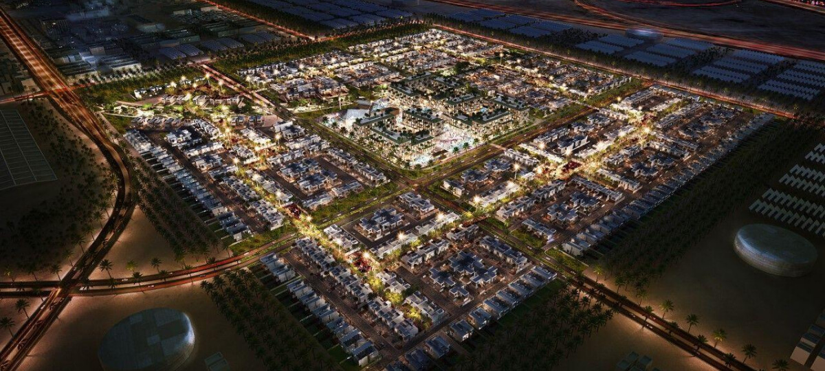 Aerial night view of a master-planned residential community in Dubai, with lit villas and roads.