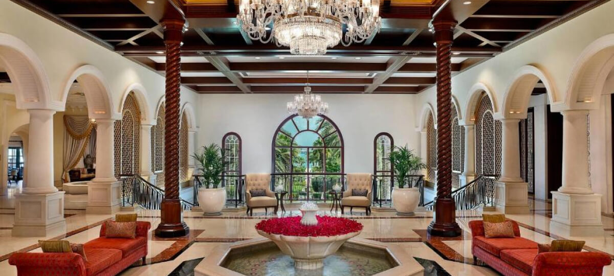 A luxurious, classical-style interior featuring grand arches, elegant chandeliers, and plush seating near large arched windows.