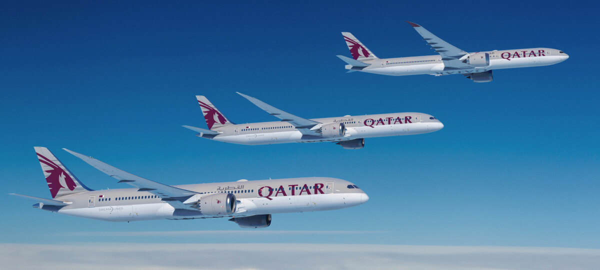 A formation of Qatar Airways Boeing 787 Dreamliner aircraft flying in clear blue skies.