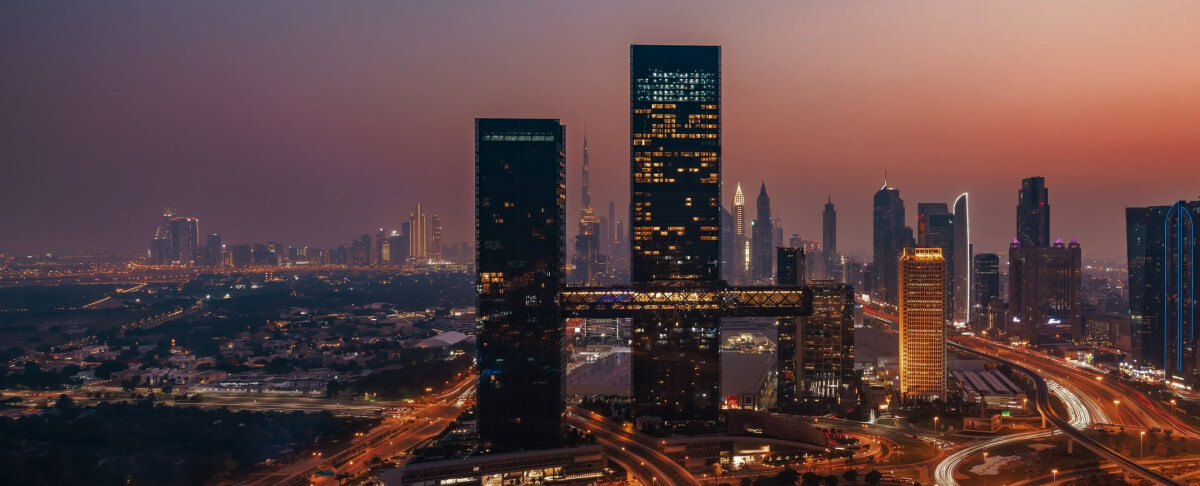 Dubai skyline illuminated at night with Sheikh Zayed Road and twin towers in view.