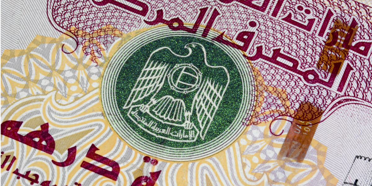 Macro image of a UAE banknote showing the national emblem.