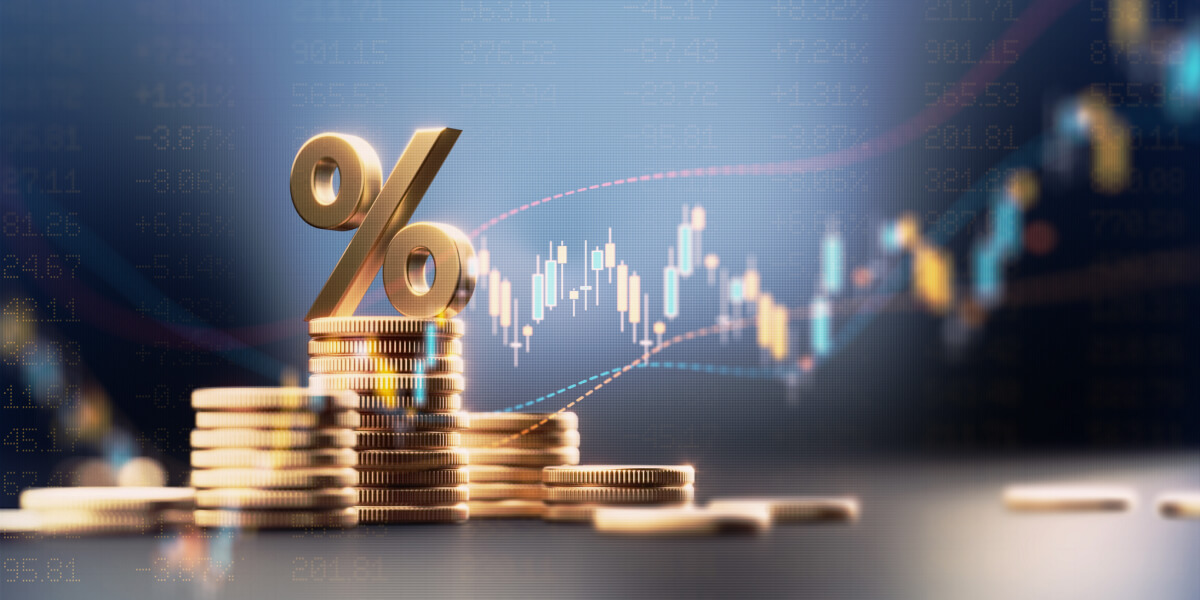  Golden percentage sign on stacked coins with financial stock market graph in the background.