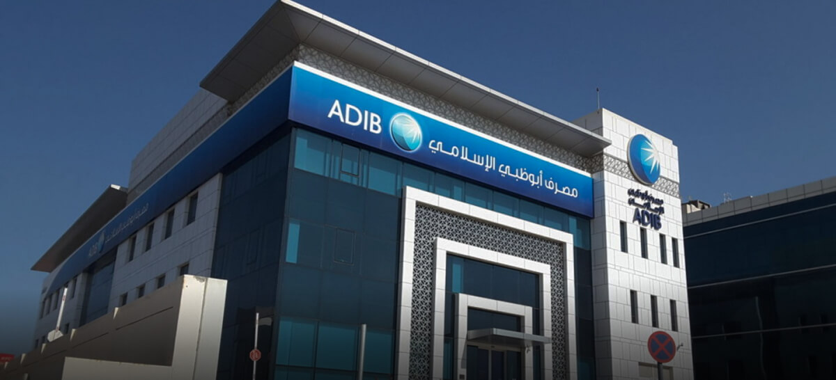 The blue and white exterior of an ADIB branch with Islamic geometric patterns and Arabic signage.