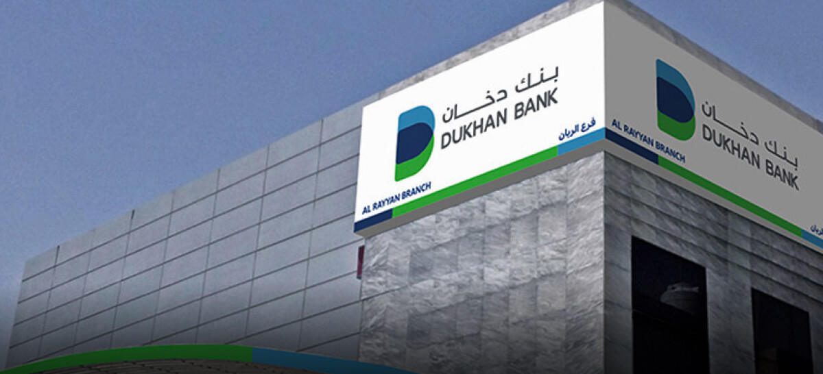 A branch of Dukhan Bank with bilingual signage is shown on a sleek, modern grey stone building.