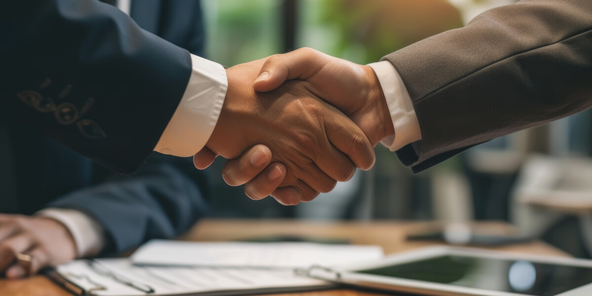 Two people in business attire firmly shake hands, symbolizing agreement or partnership.