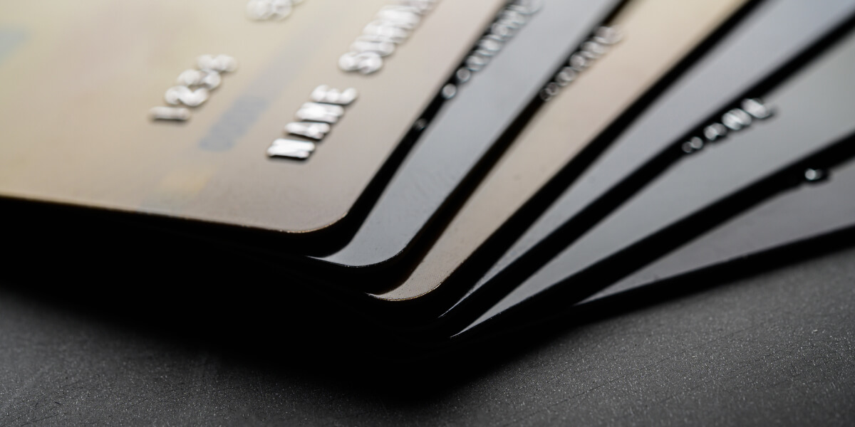 Close-up of several stacked black credit cards with embossed numbers in sharp focus.