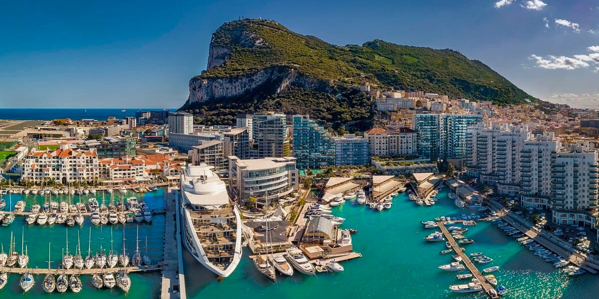 Gibraltar’s skyline framed by modern buildings, yachts, and the iconic Rock of Gibraltar rising in the background.