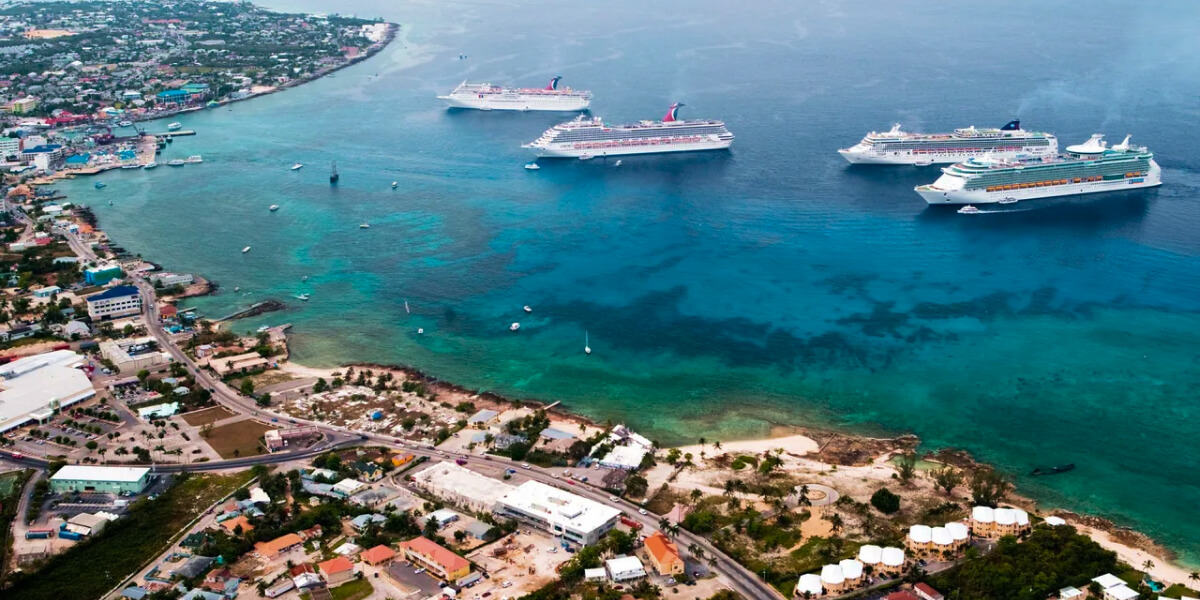 Two cruise ships float near the coast of a tropical Caribbean island.