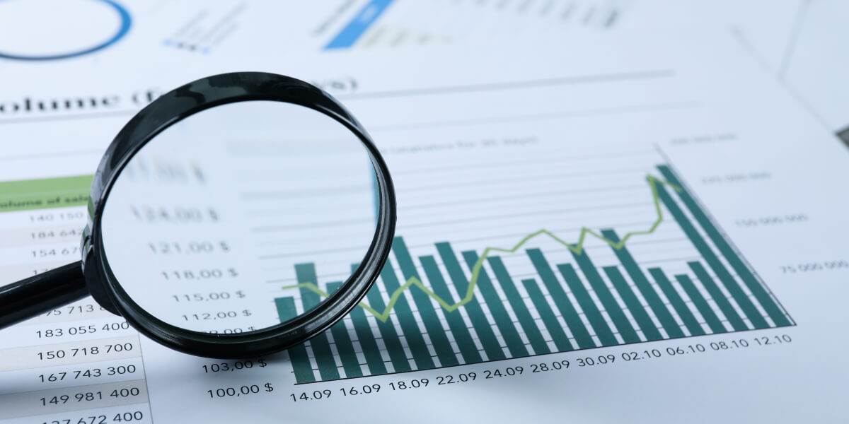  A magnifying glass focuses on a financial report with numbers and bar graphs.